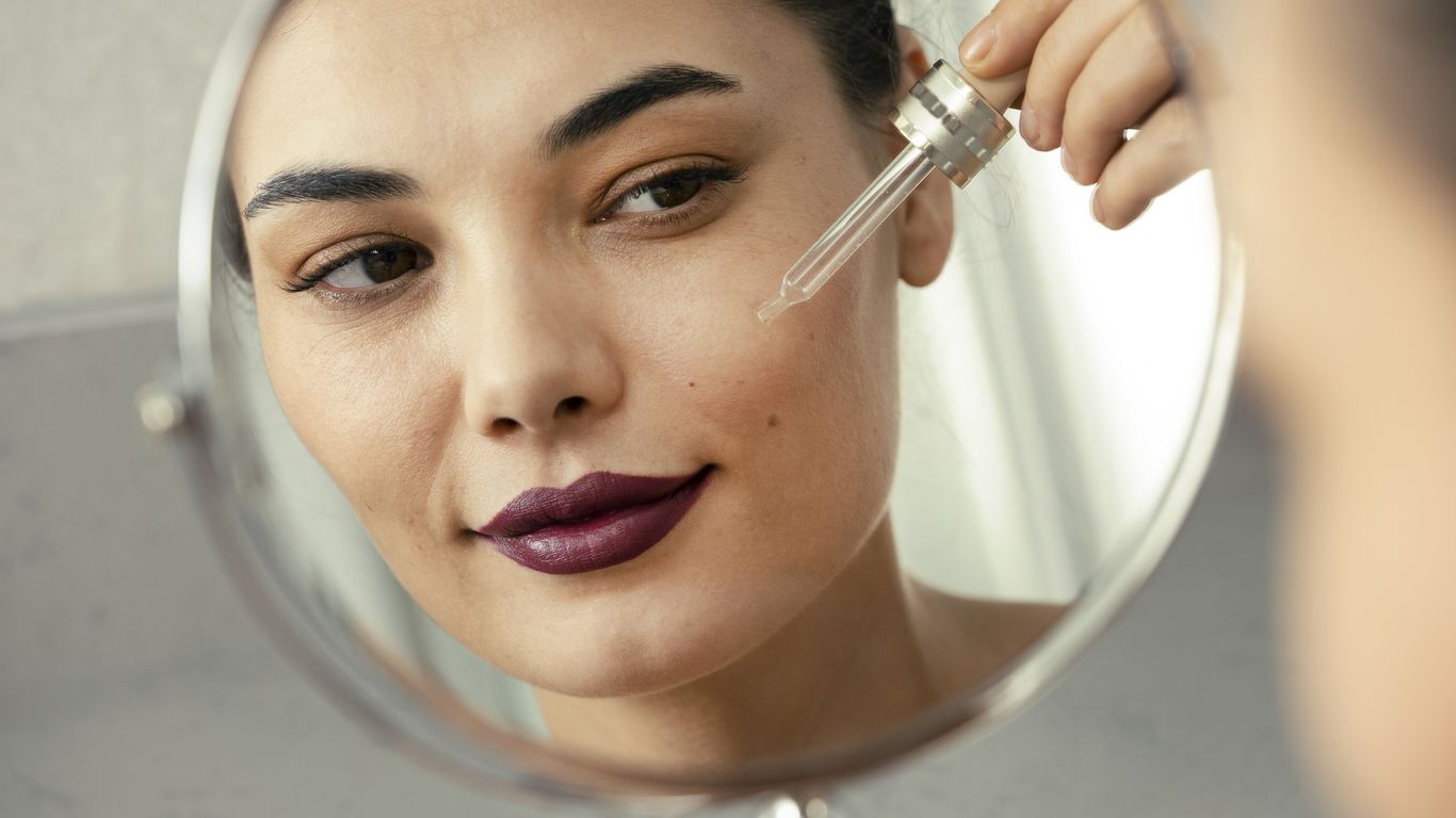 A young woman uses retinol Korean skincare products in the mirror