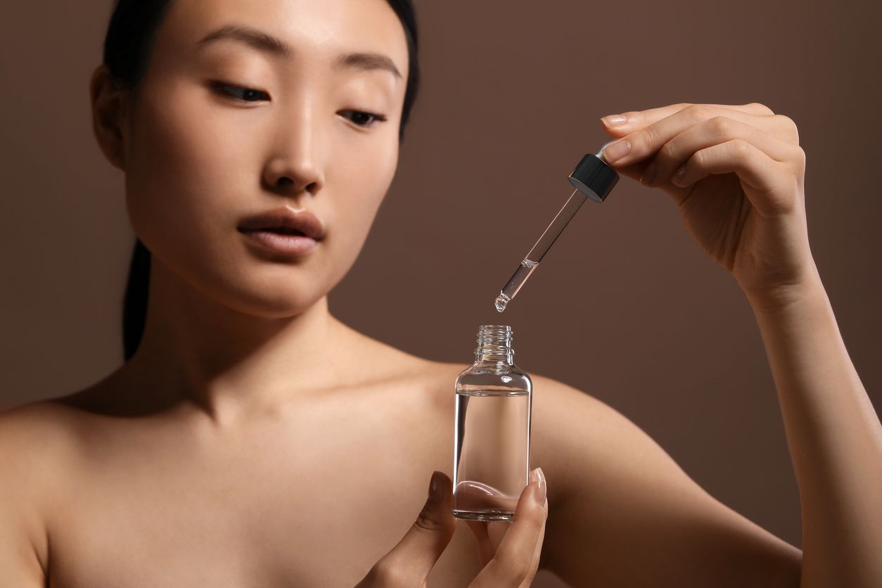 Young woman using a dropper bottle, showing how to get glass skin.