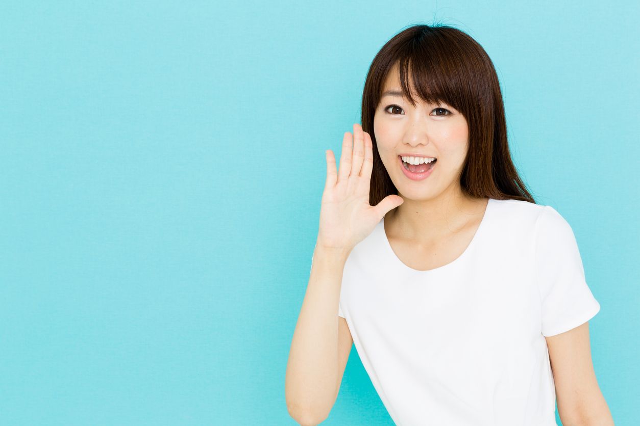 A young woman holds her hand up to her mouth with a smile as she shares Korean beauty hacks
